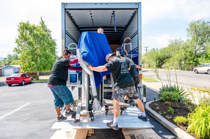 Happy Home Movers crew loading protected furniture into a moving truck with professional equipment