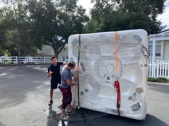 Happy Home Movers crew securing a wrapped hot tub for safe transport